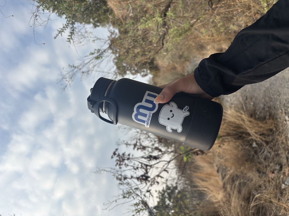Botella con stickers de MellowFit en un sendero